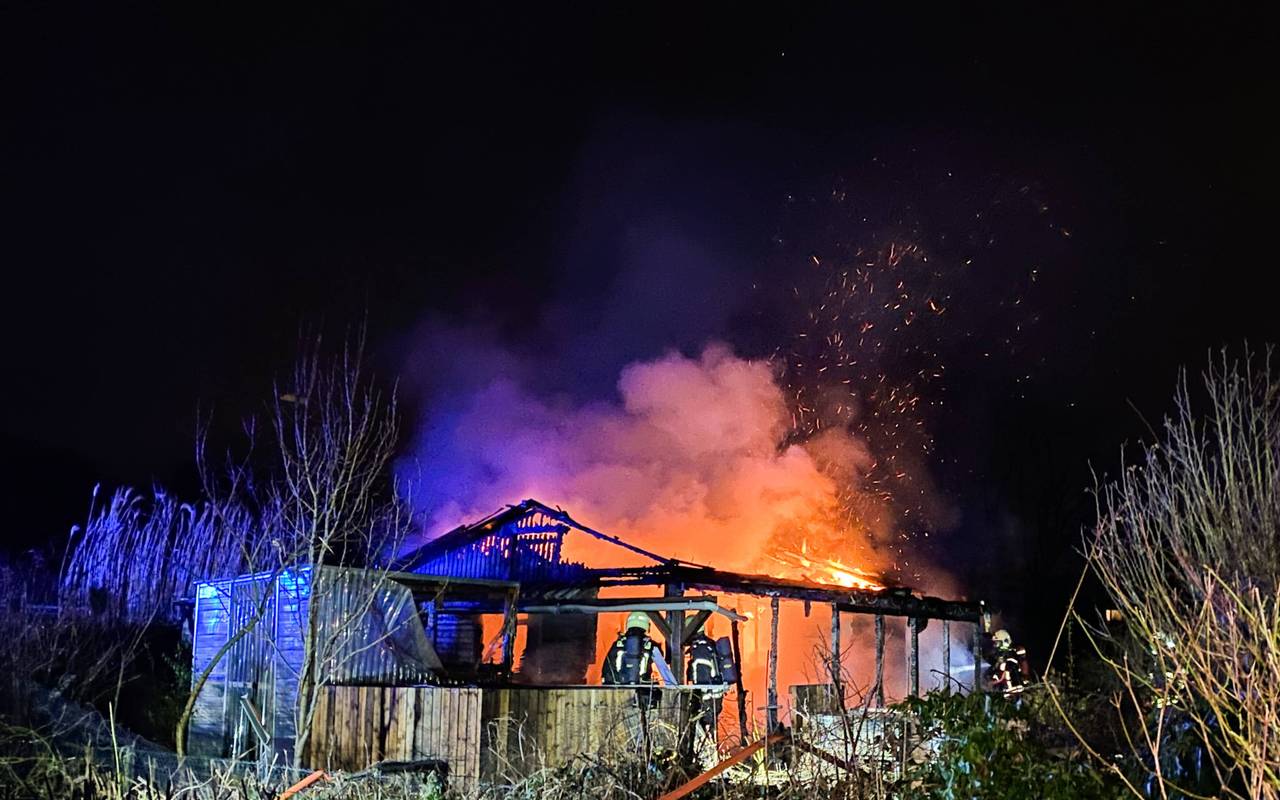 Die Gartenlaube in Herten-Scherlebeck steht komplett in Flammen. Feuerwehrleute versuchen sie zu löschen.