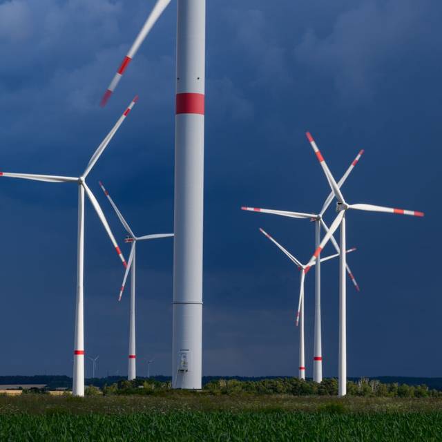 Dunkle Gewitterwolken ziehen über einen Windenergiepark.