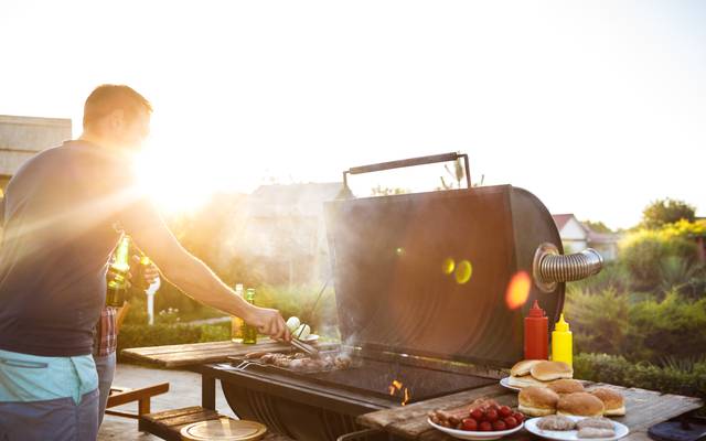 Mann grillt an Gasgrill