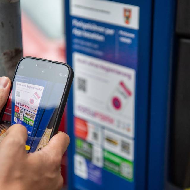 Ein Mann scannt den QR-Code einer Park-App mit einem Smartphone