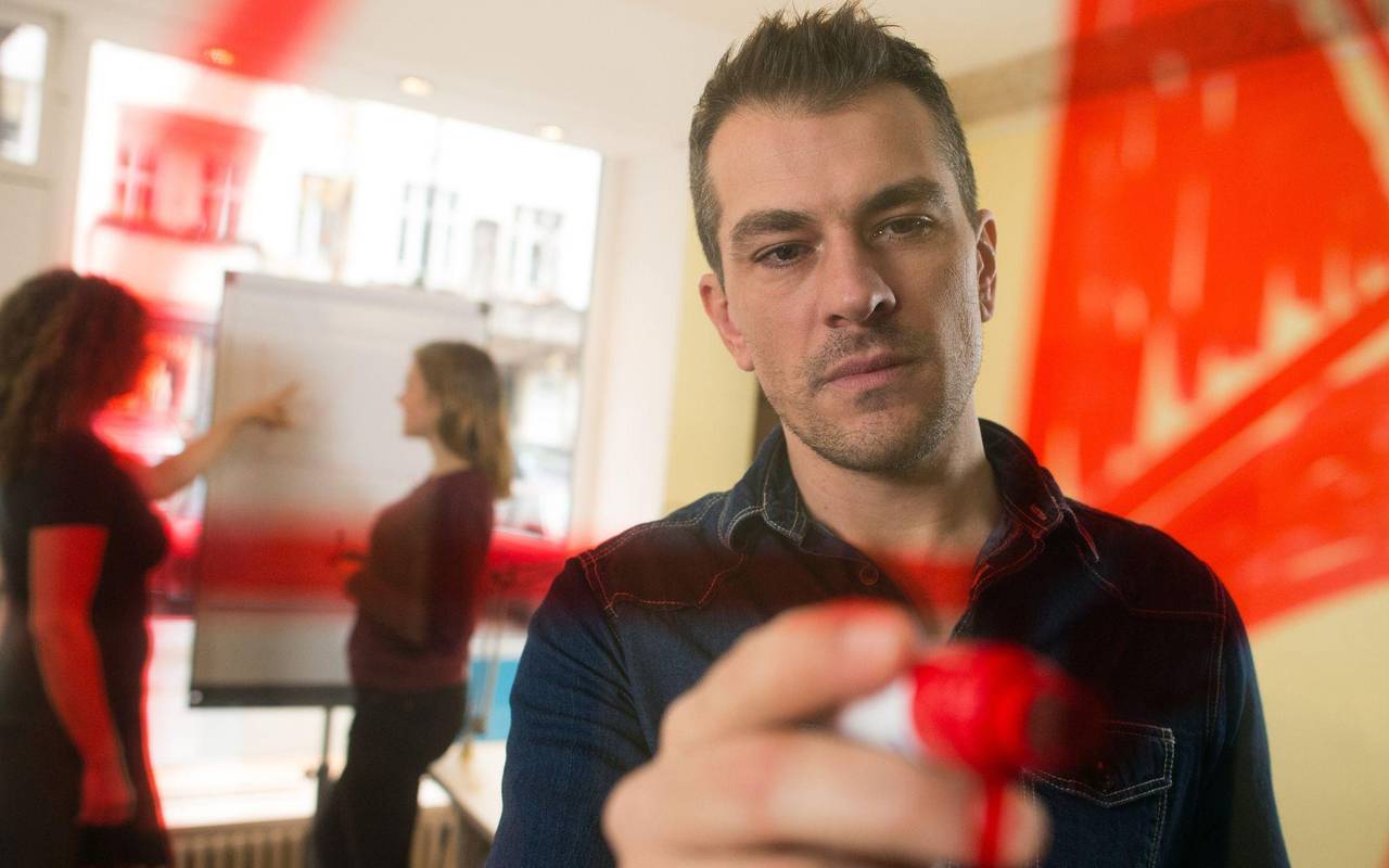 Mann malt zur Visualisierung einen Kreis an eine Plexiglasscheibe