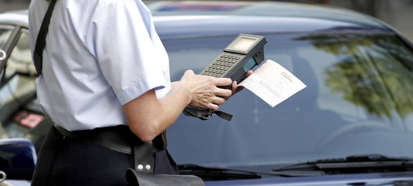 Eine Politesse stellt einem Parksünder ein Bußgeld aus (Symbolbild).