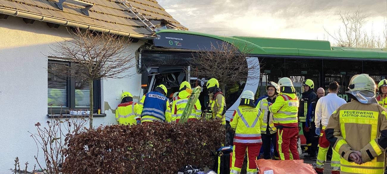 Mehrere Rettungskräfte stehen an dem Unfallbus und versuchen den Busfahrer aus seiner Kabine zu befreien.