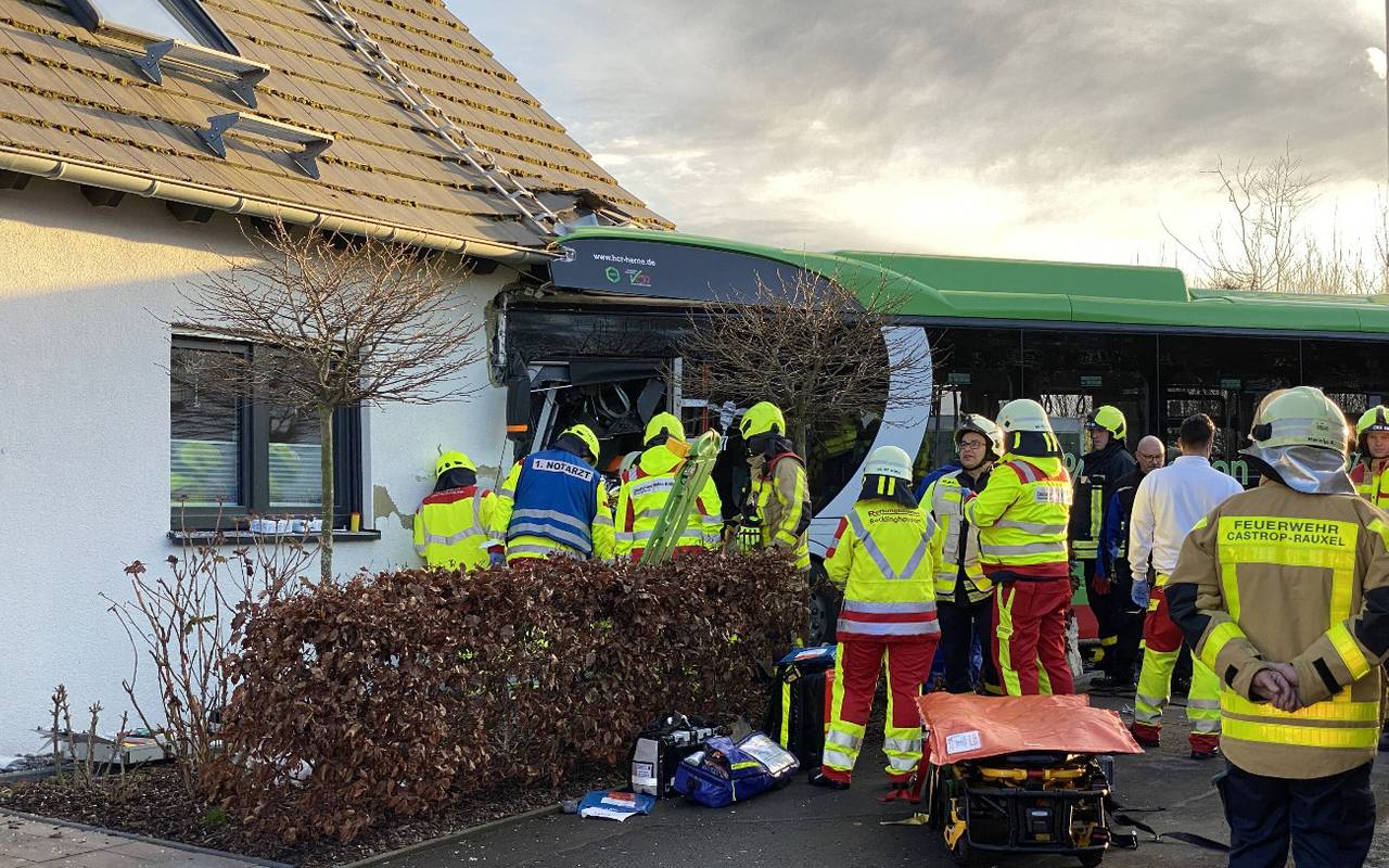 Mehrere Rettungskräfte stehen an dem Unfallbus und versuchen den Busfahrer aus seiner Kabine zu befreien.