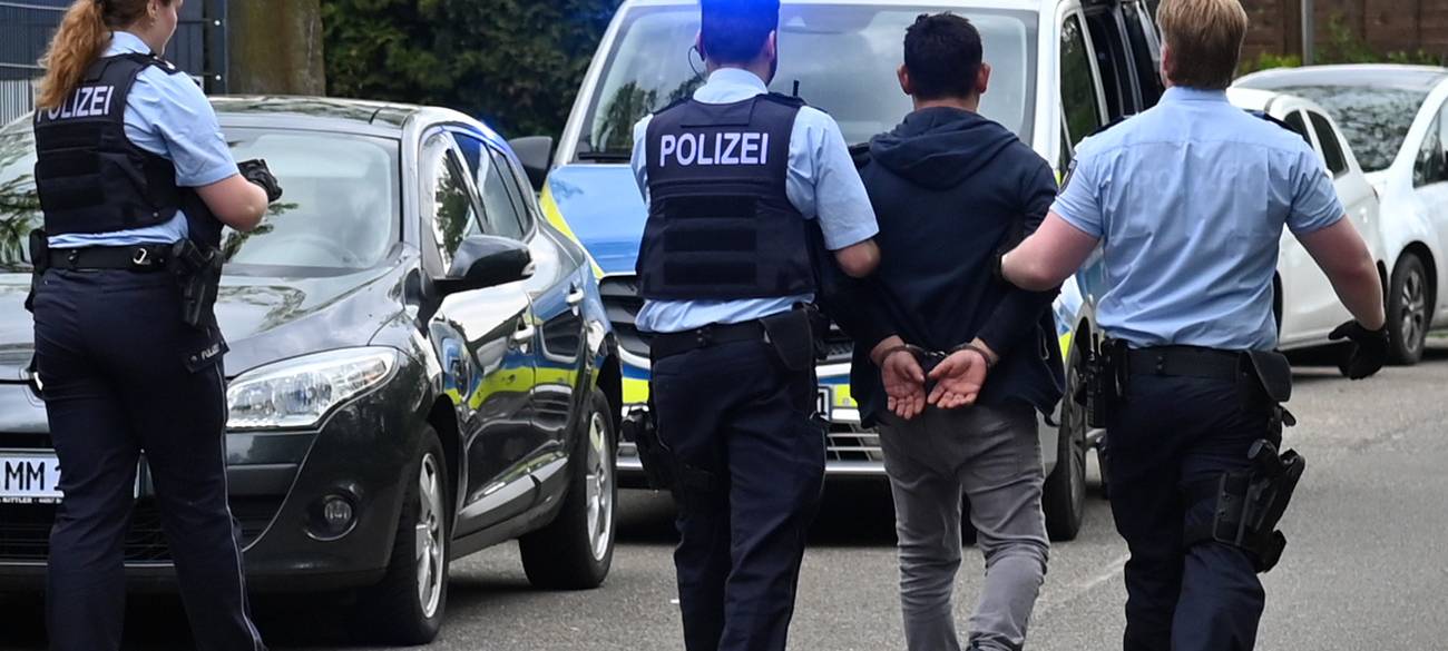 Der mutmaßliche Täter wird von der Polizei in Handschellen abgeführt.