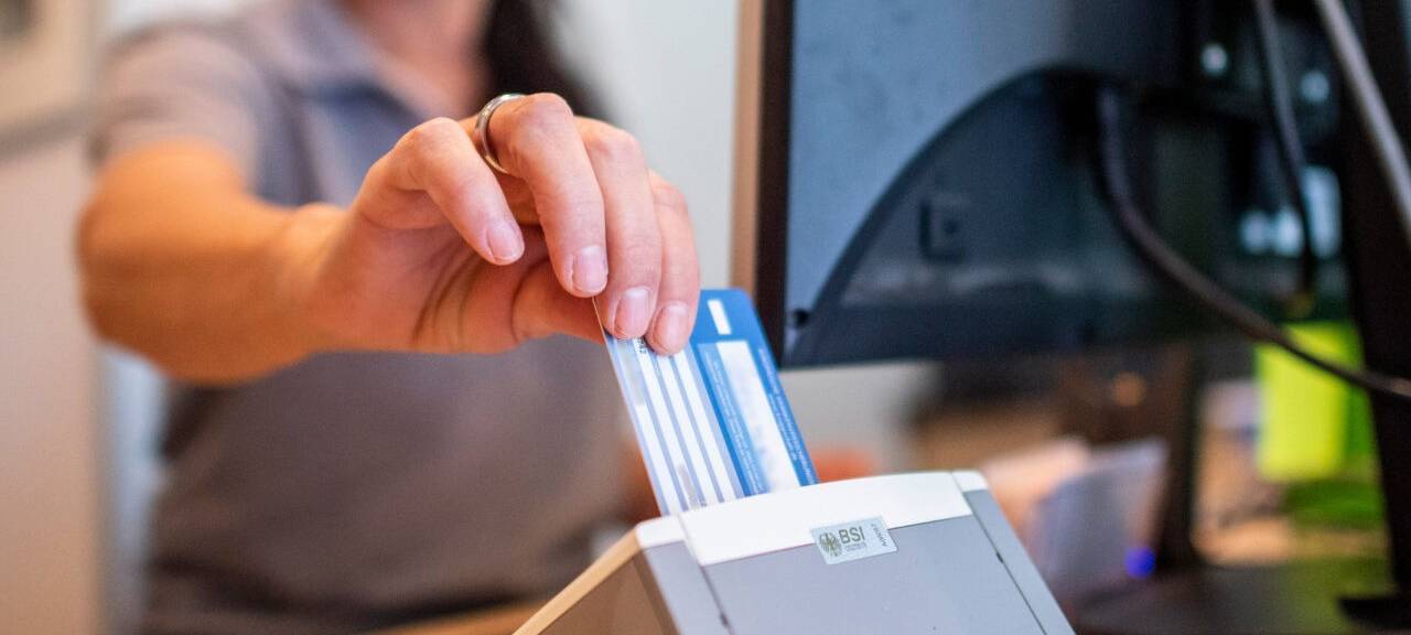 Eine Person schiebt eine Versichertenkarte einer Krankenkasse in eine Lesegerät. Elektronische Rezepte und digitale Patientenakten sollen nach jahrelangen Verzögerungen auf breiter Front zum Einsatz kommen. Darauf zielen Gesetzespläne von Gesundheitsminister Lauterbach (SPD), die das Bundeskabinett am Mittwoch in Meseberg auf den Weg gebracht hat.