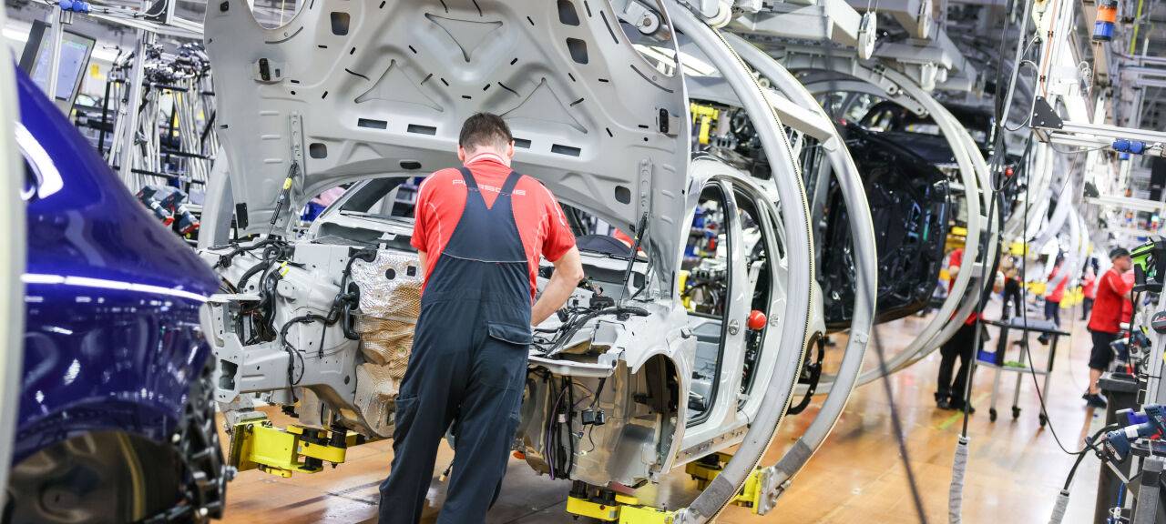 Ein Mitarbeiter montiert einen Porsche Macan in einem Werk.