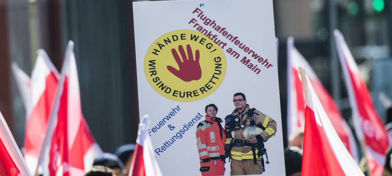 in Plakat "Hände weg! Wir sind Eure Rettung" wird von einem Mitglied der Flughafen Feuerwehr Frankfurt auf einer Demonstration gehalten. Rettungskräfte demonstrieren in der Banken-Metropole für mehr Respekt und gegen Gewalt bei ihren Einsätzen
