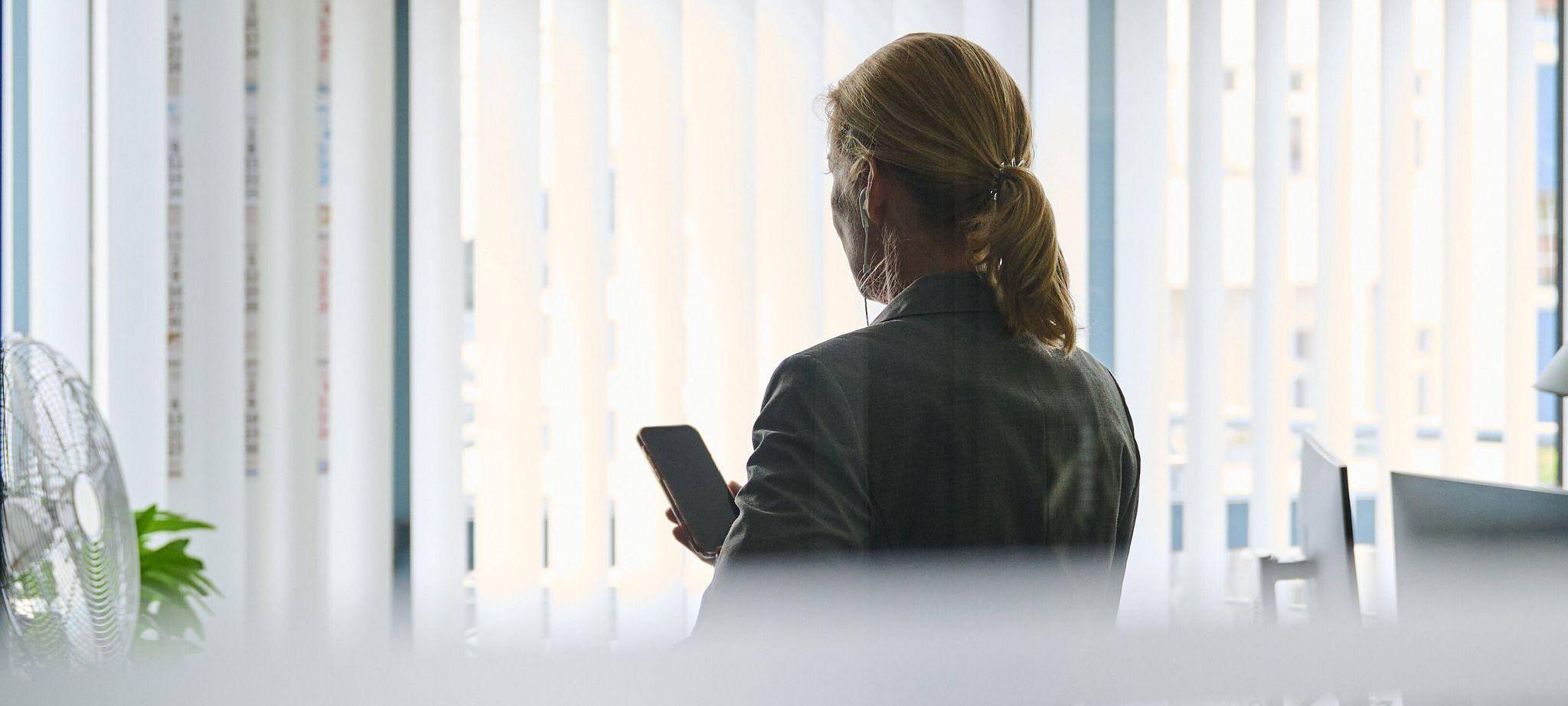 Frau steht im Büro und telefoniert mit einem Headset