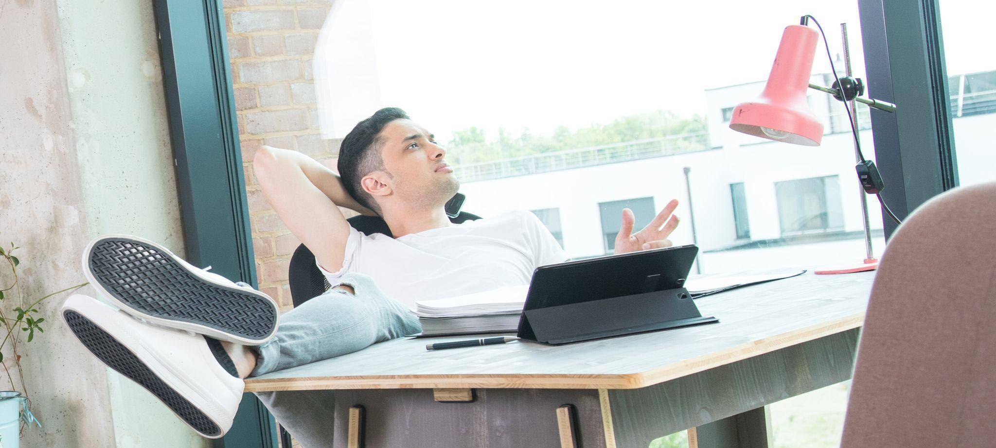 Mann schaut an seinem Schreibtisch aus dem Fenster