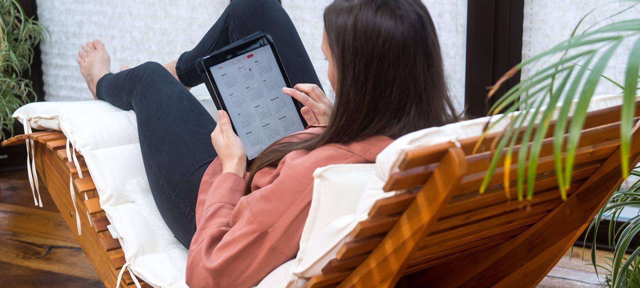 Eine Frau guckt auf einem Tablet auf einen Kalender