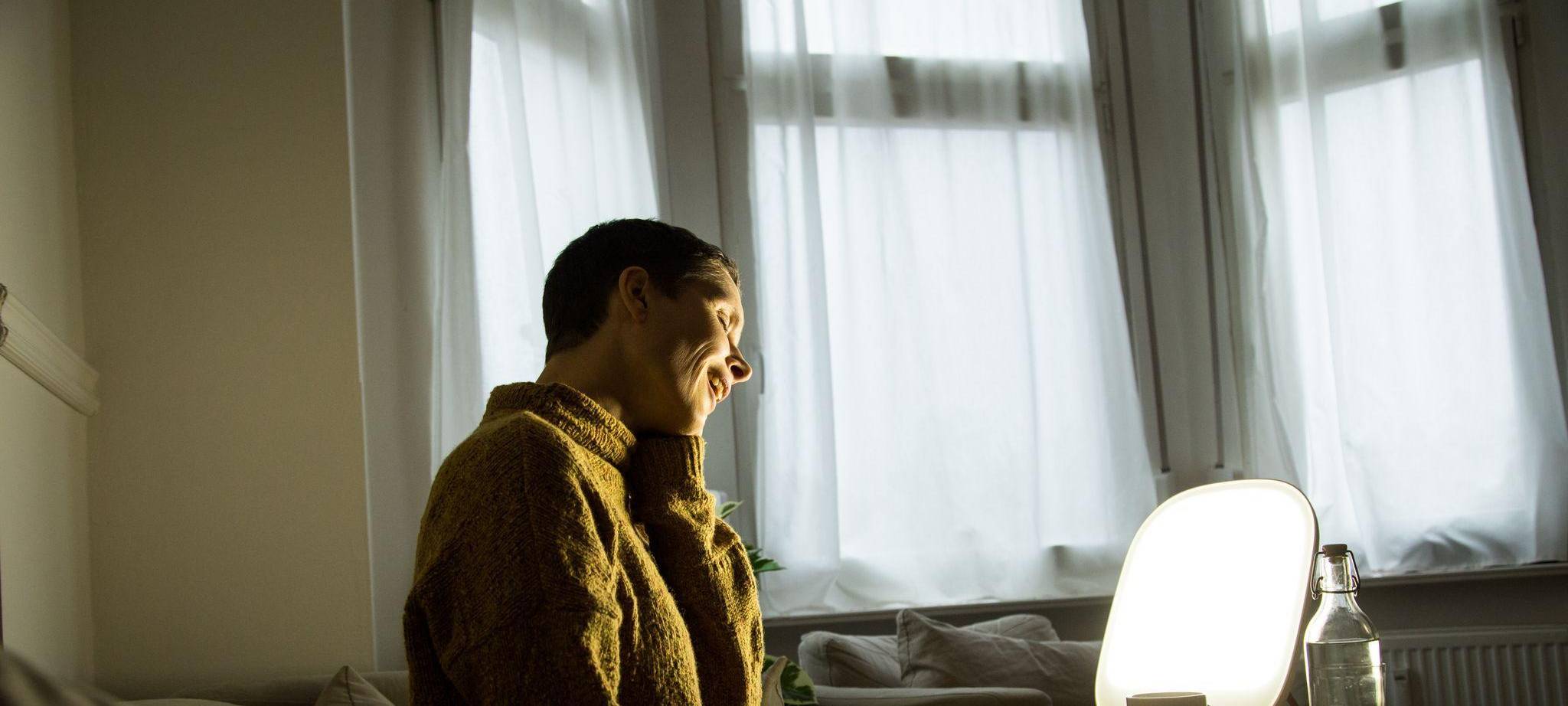 Frau sitzt vor einer Tageslichtlampe