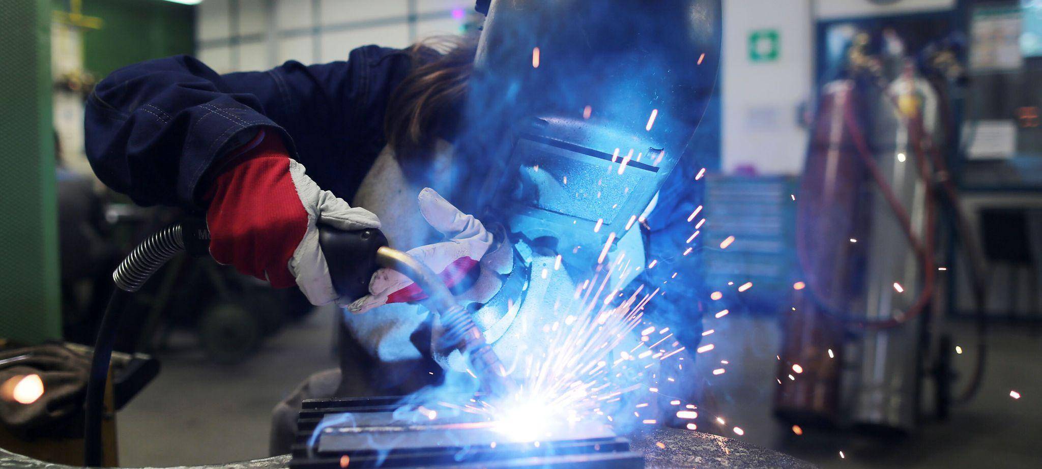 Eine Auszubildende zum Schweißer arbeitet einem Stück Metall