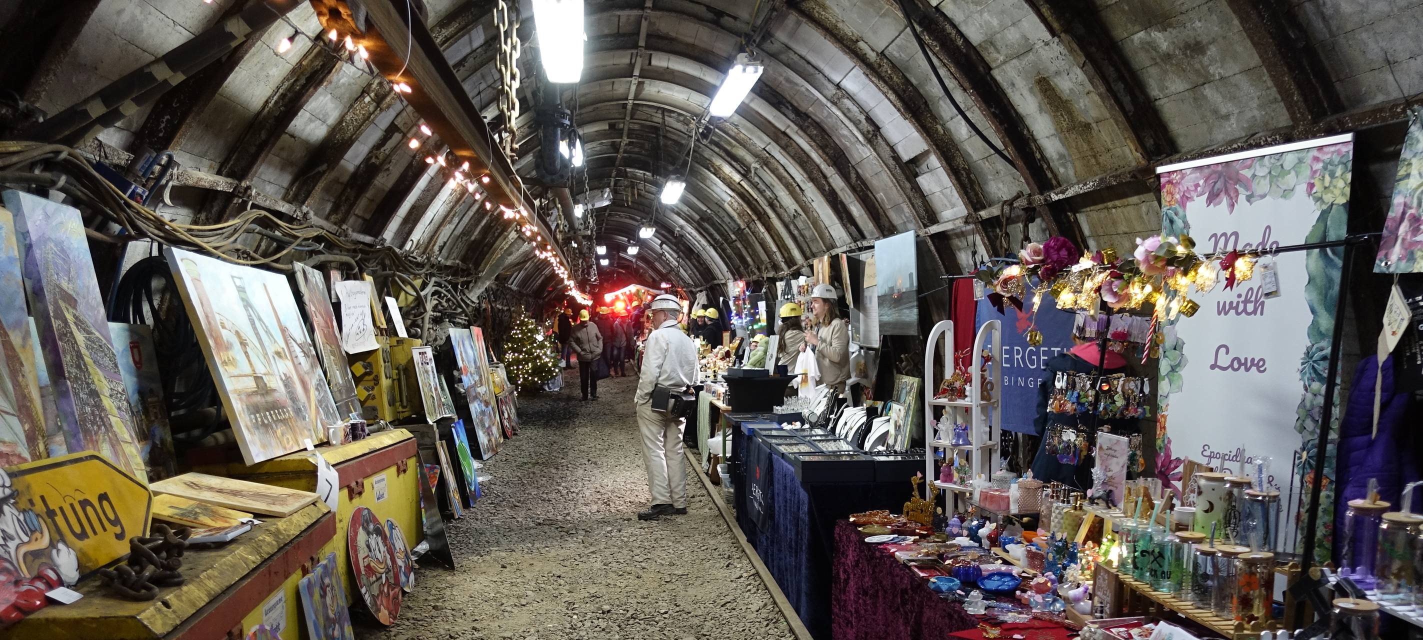 Ein langer, enger Stollen. Rechts und Links befinden sich Weihnachtsmarktstände.
