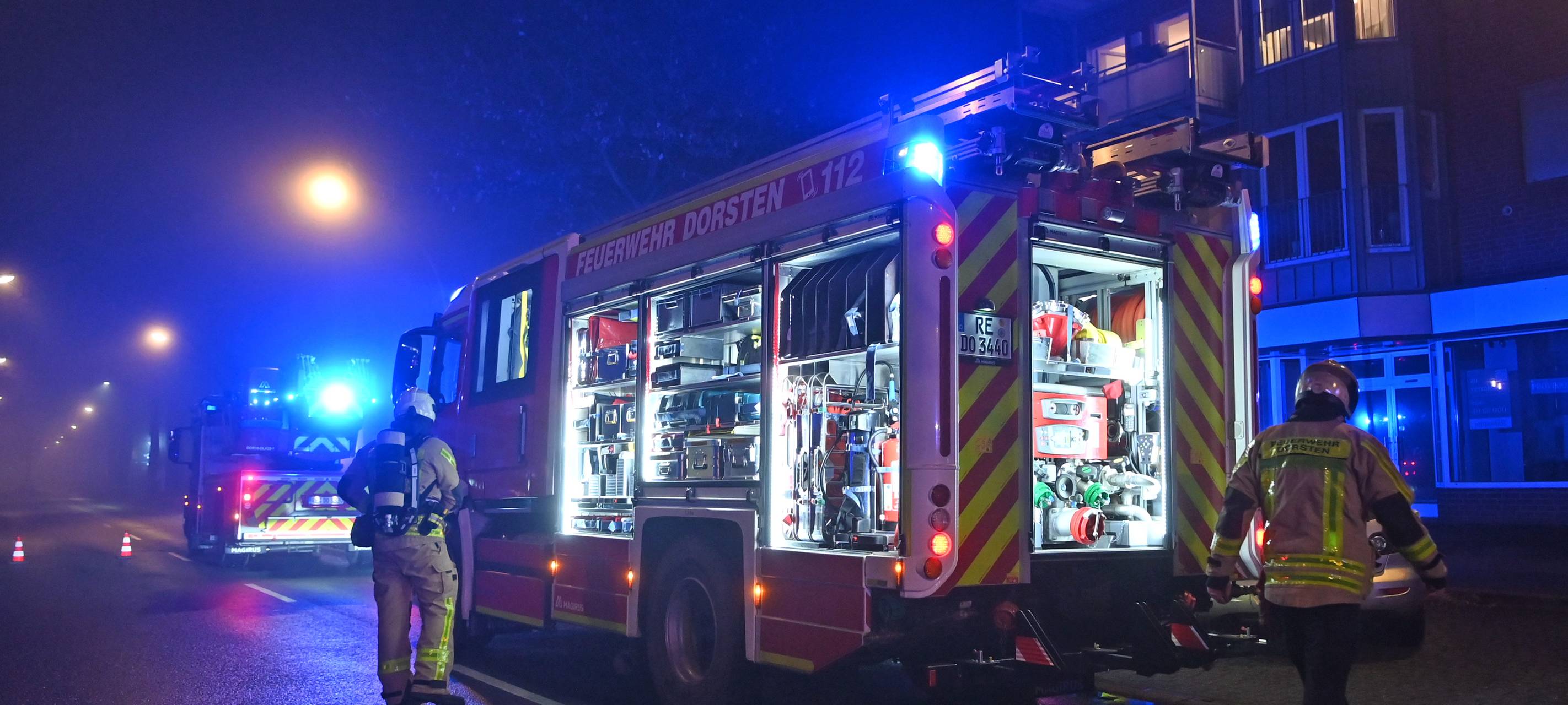 Ein Feuerwehrauto der Feuerwehr Dorsten steht mit eingeschaltetem Blaulicht vor einem Haus