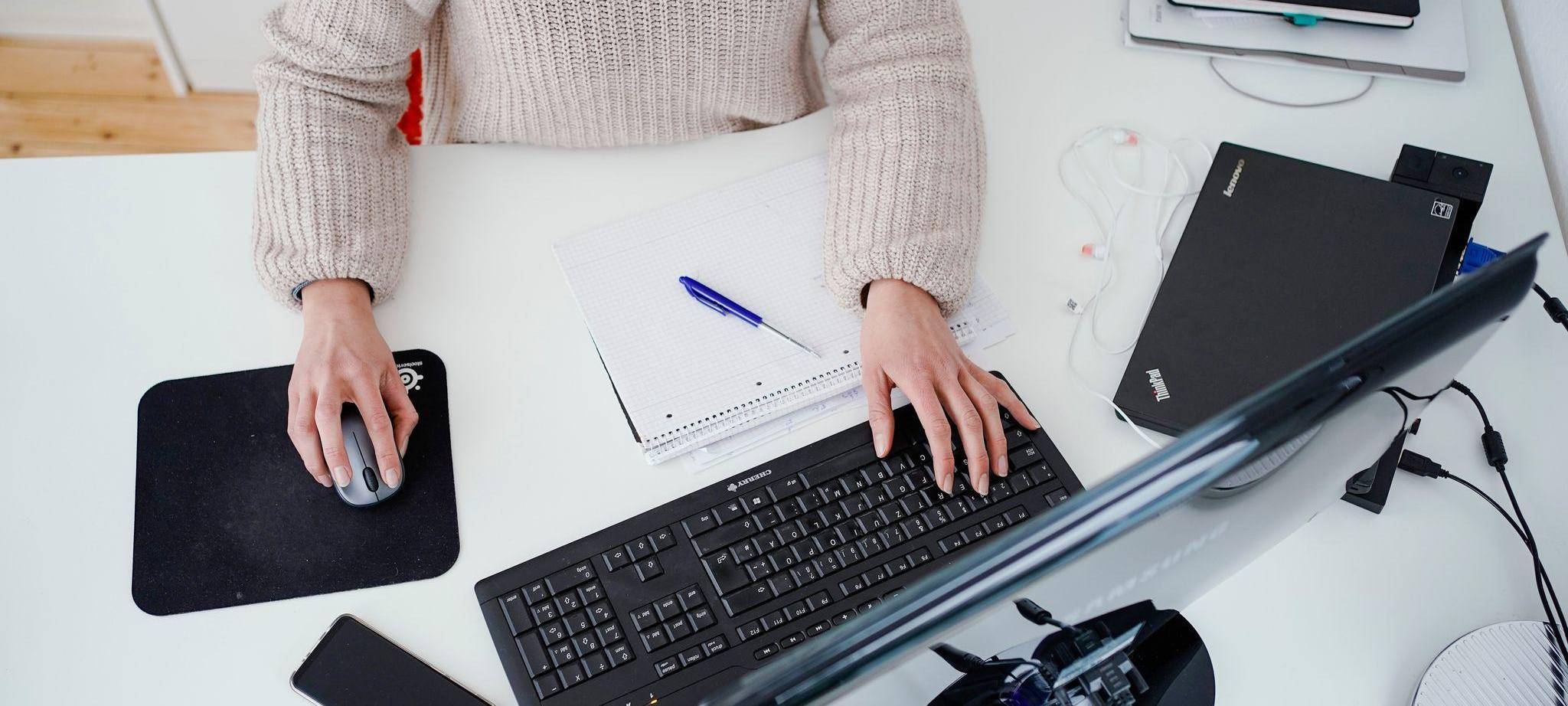 Eine Person arbeitet im Homeoffice an einem Schreibtisch