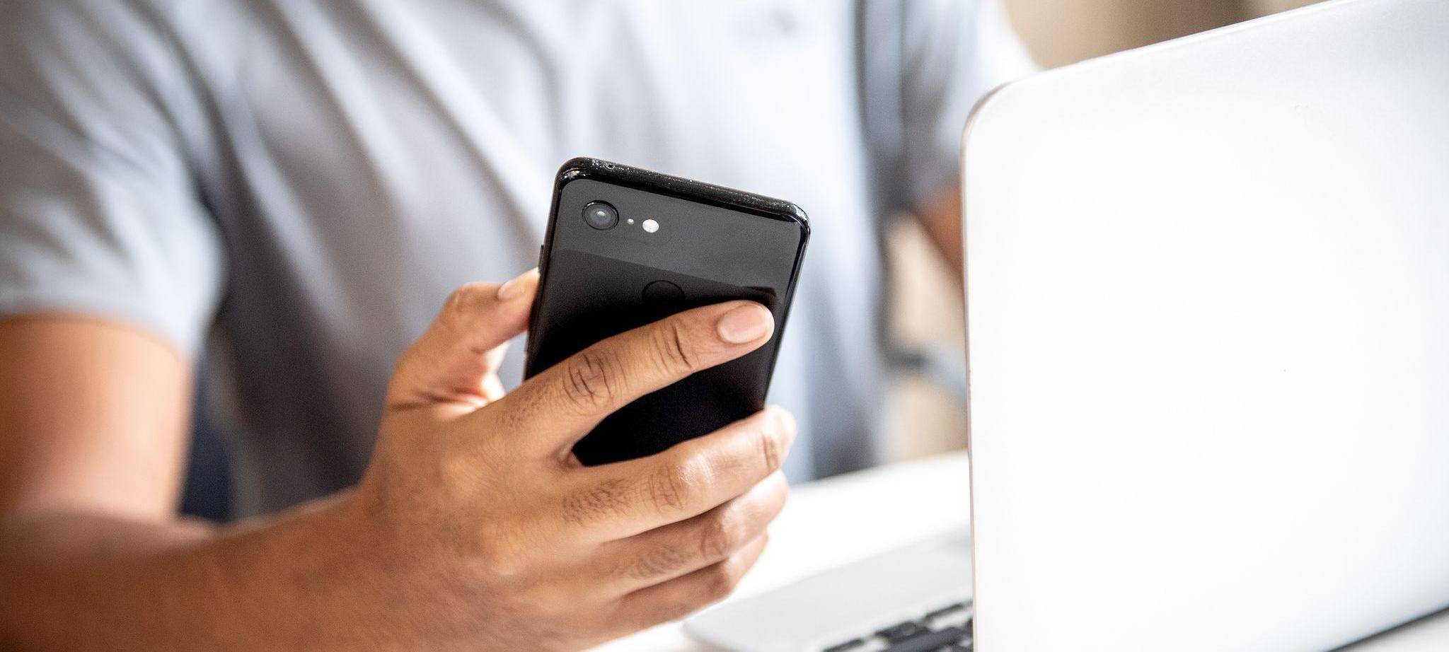 Mann mit Smartphone und Laptop