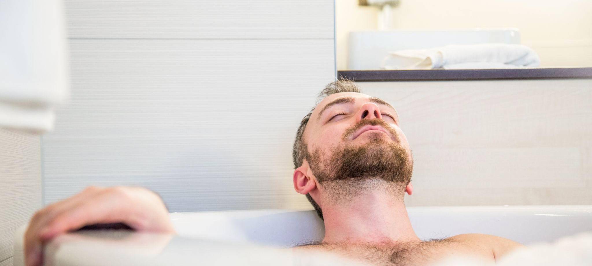 Ein Mann liegt mit geschlossenen Augen in der Badewanne