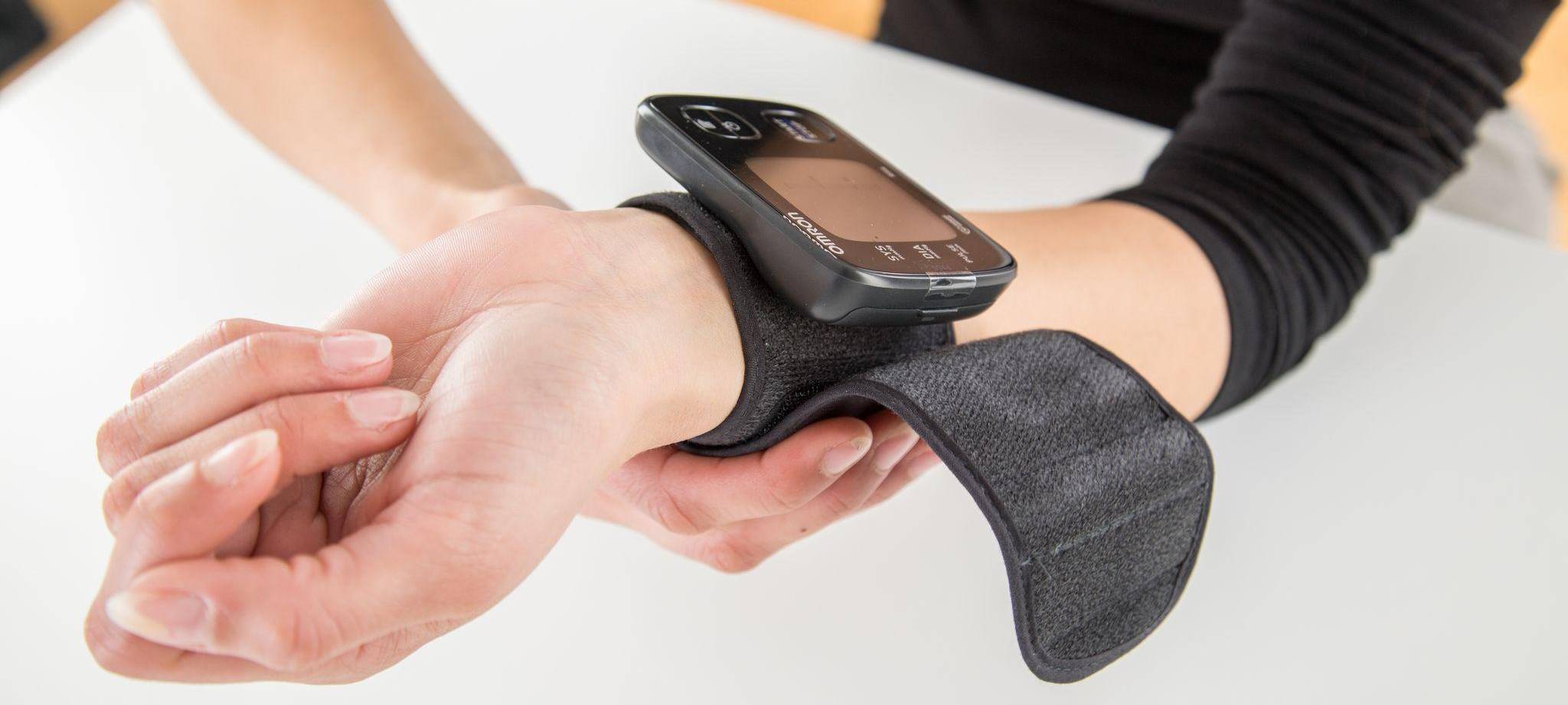 Frau misst ihren Blutdruck am Handgelenk