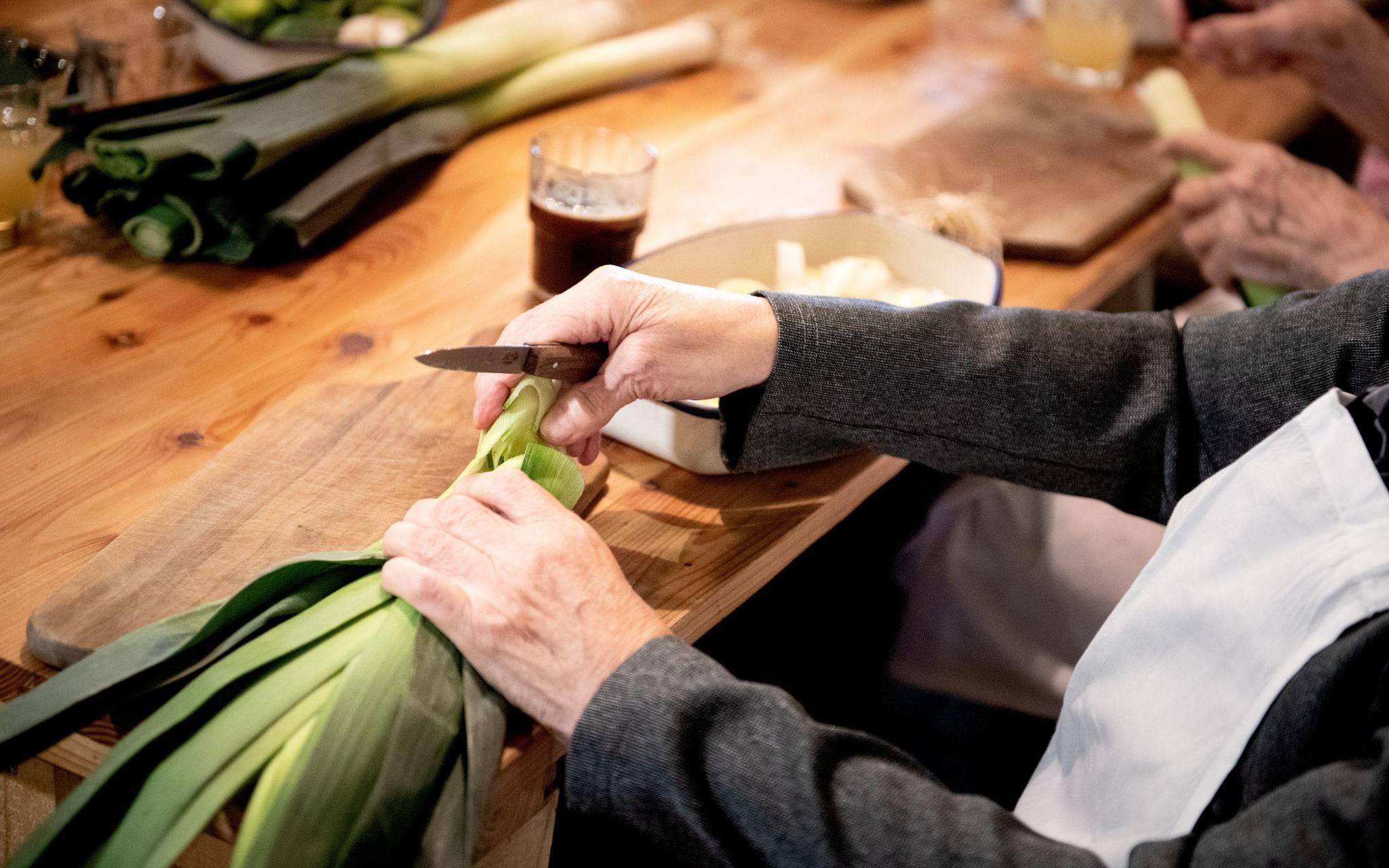 Eine Seniorin schneidet Lauch klein