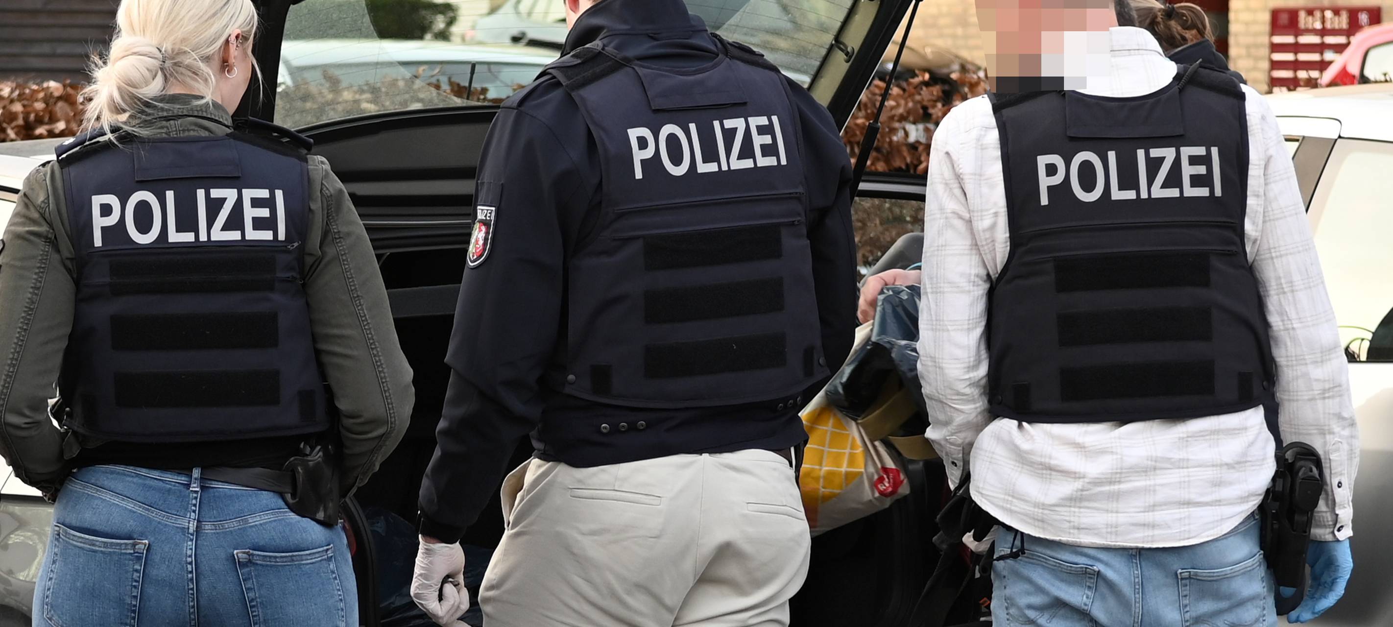 Mehrere Polizisten stehen vor einem geöffneten Kofferraum eines Autos in Dorsten-Lembeck.