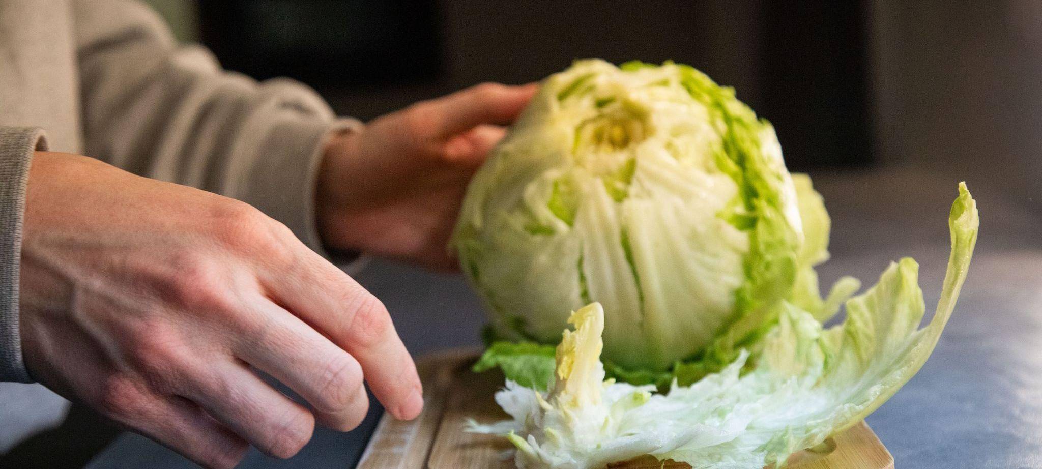 Frau entfernt den Strunk an einem Salatkopf
