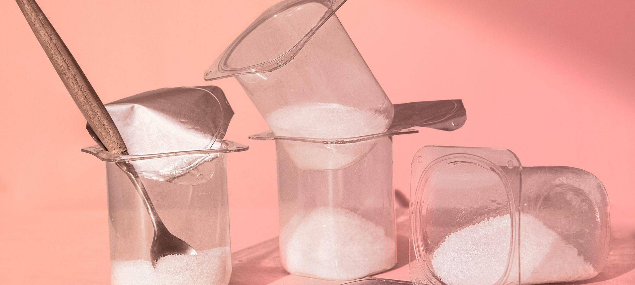 Mit Zucker gefüllte Joghurtbecher stehen auf einem Tisch
