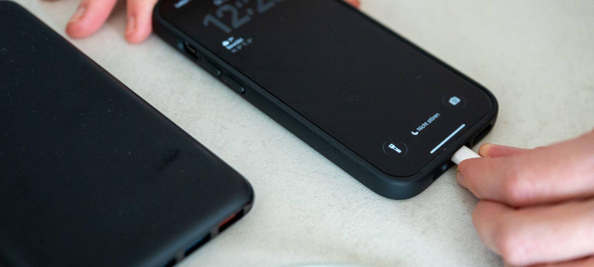 Eine Frau schließt ein iPhone an eine Powerbank an