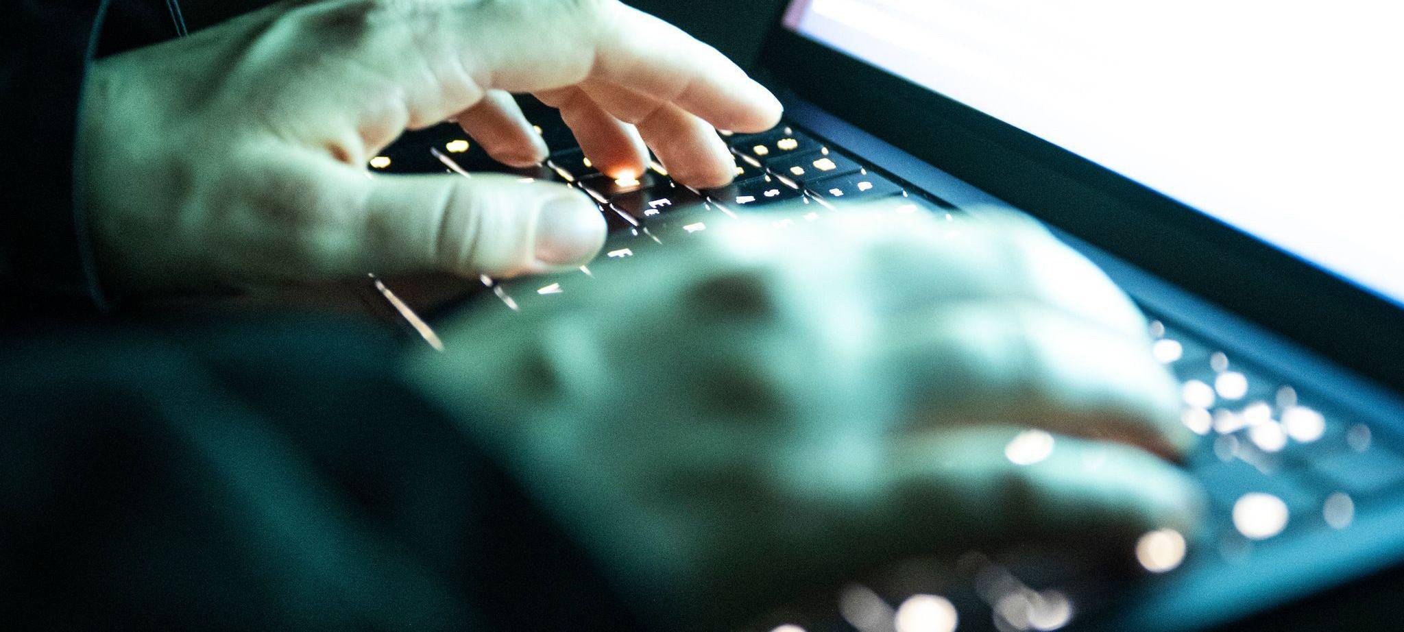 Eine Person tippt auf einer beleuchteten Laptop-Tastatur