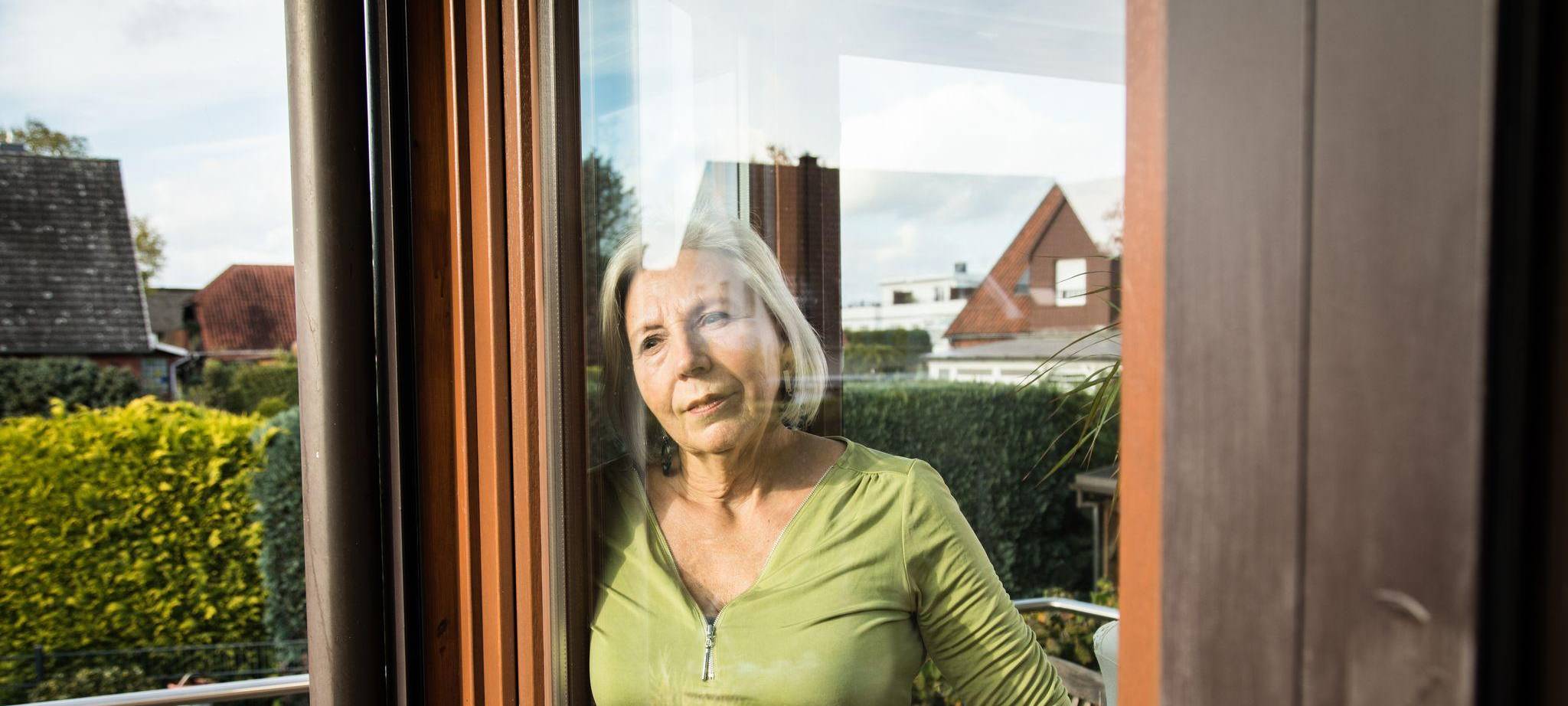 Eine Frau blickt aus einem Fenster auf einen Garten