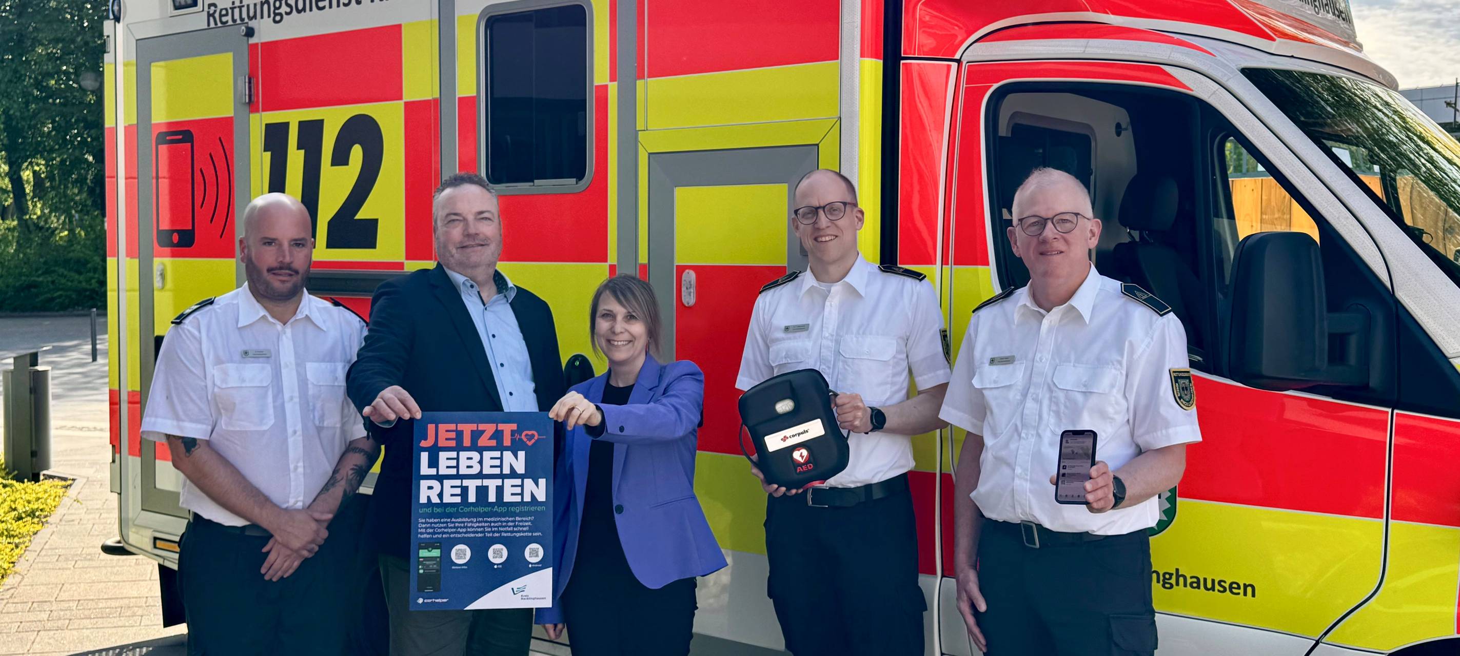 Verantwortliche stehen vor einem Rettungswagen und präsentieren die neue Lebensretter-App für den Kreis Recklinghausen
