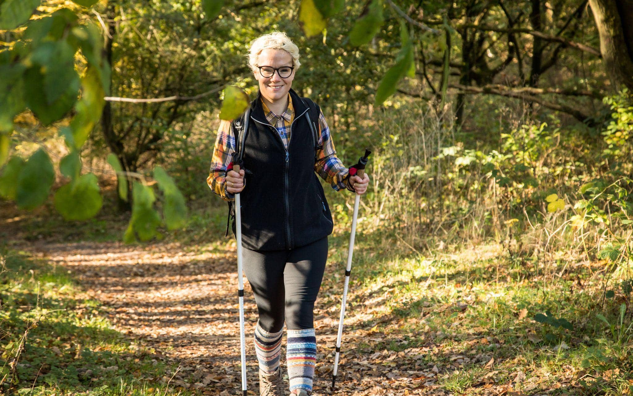 Eine Frau wandert mit Wanderstöcken durch den Wald