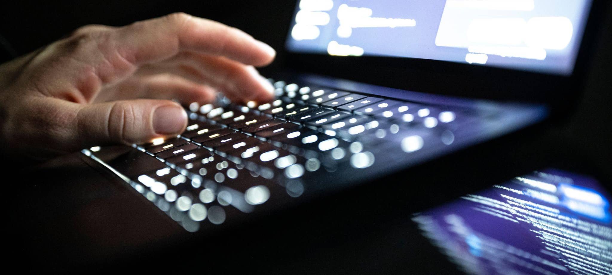 Eine Person tippt auf einer beleuchteten Laptop-Tastatur