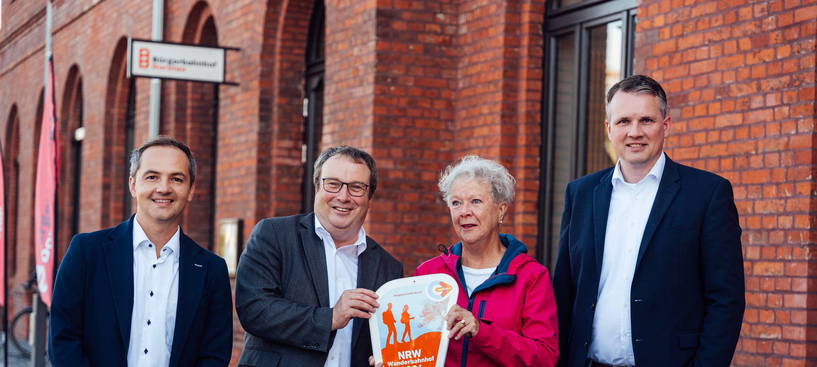 NRW-Verkehrsminister Oliver Krischer (2.v.l.) hat der Stadt Dorsten die offizielle Plakette für den NRW-Wanderbahnhof 2026 übergeben.