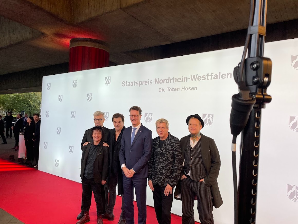 Die Toten Hosen und NRW-Ministerpräsident Hendrik Wüst auf dem rote Teppich. Die Toten Hosen bekommen den NRW-Staatspreis für  ihr kulturelles Lebenswerk und für ihre sozialen Einsatz.