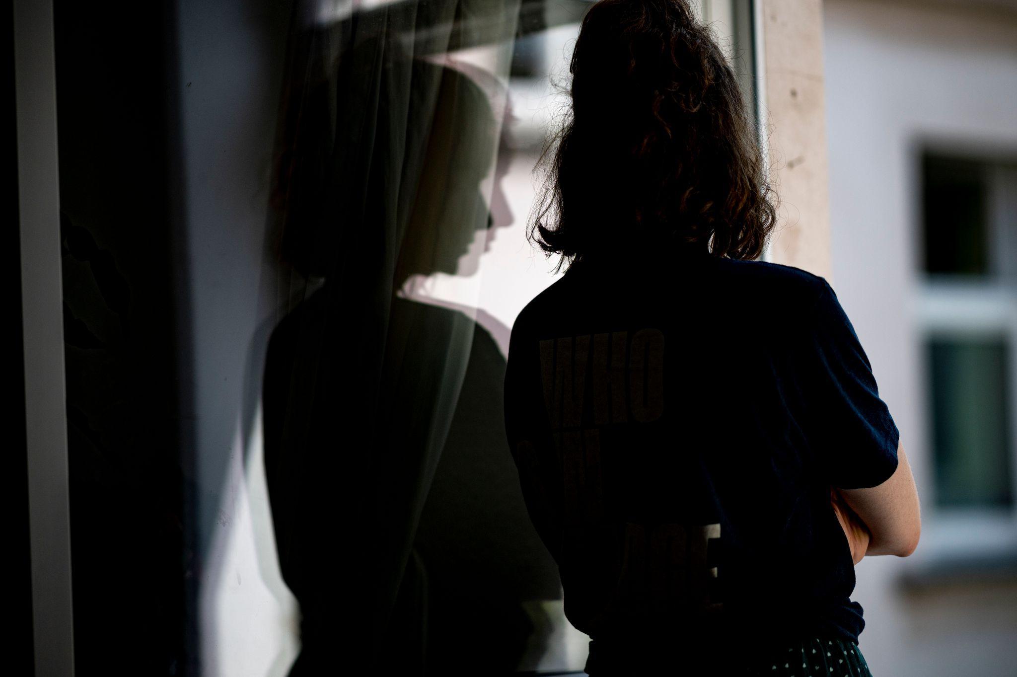 Frau schaut besorgt aus dem Fenster