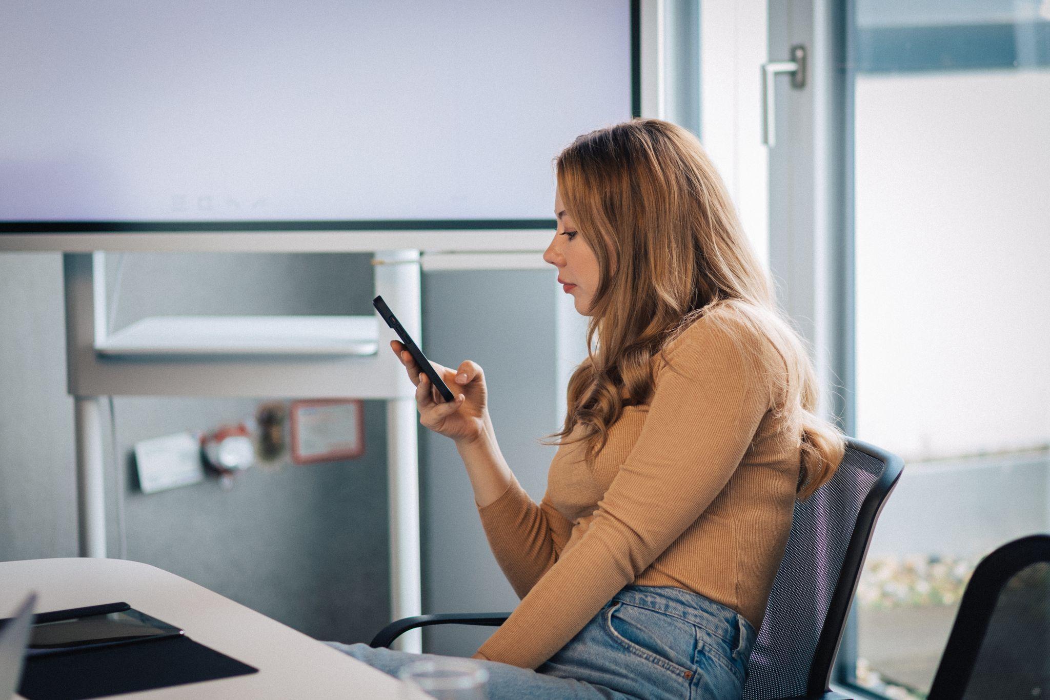 Eine Frau blickt auf ihr Smartphone in einem Konferenzraum