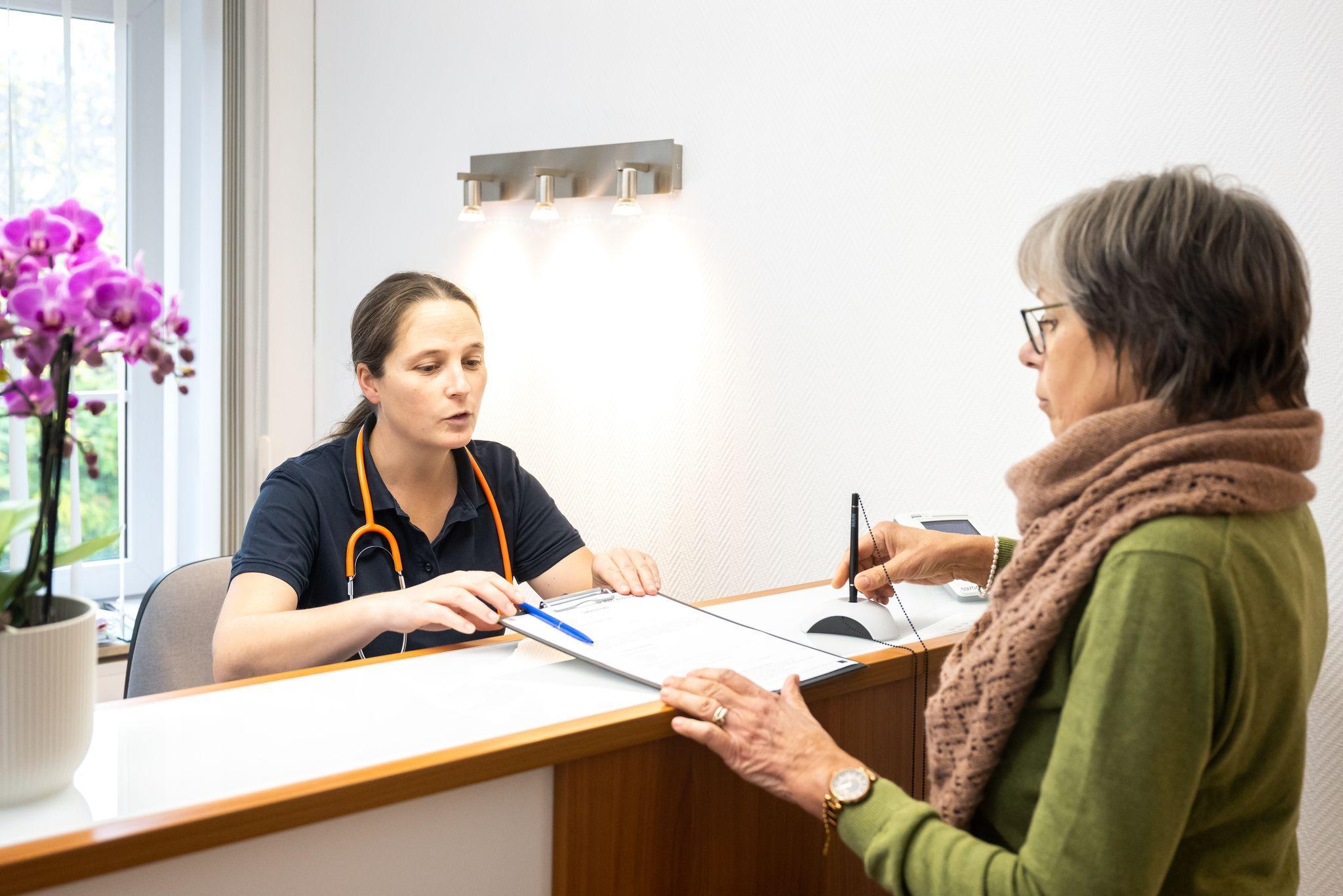 Eine Patientin wird von einer Sprechstundenhilfe beraten